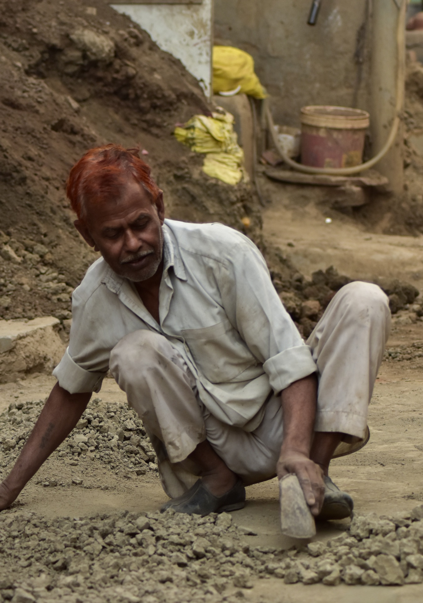 A labourer at rest on a dust-filled street