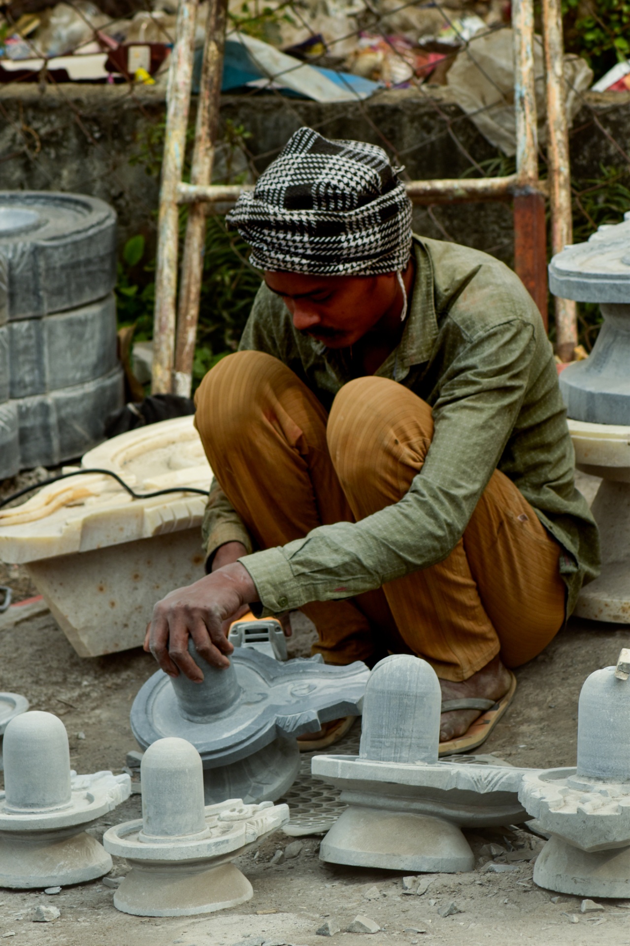 A craftsman polishing stone lingams on the roadside
